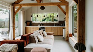Een gezellig interieur met een houten plafond, een bank, een keuken en grote ramen.