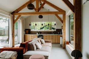 Ein gemütliches Interieur mit Holzboden, einer Couch, einer Küche und großen Fenstern.