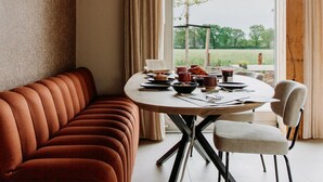 Een eetgedeelte met een ronde tafel, stoelen en een hanglamp.