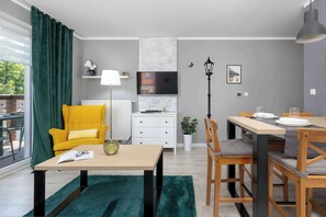 Un soggiorno moderno con un divano, un tavolo da pranzo, una TV e una pianta.