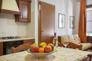 A dining table with a bowl of fruit, a wine bottle, and a glass. - Apartment 'Giallo' with Terrace, Wi-Fi and Air Conditioning (San Vito Lo Capo)