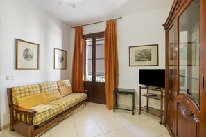 A living room with a sofa, a television on a stand, and a cabinet. - Apartment 'Giallo' with Terrace, Wi-Fi and Air Conditioning (San Vito Lo Capo)