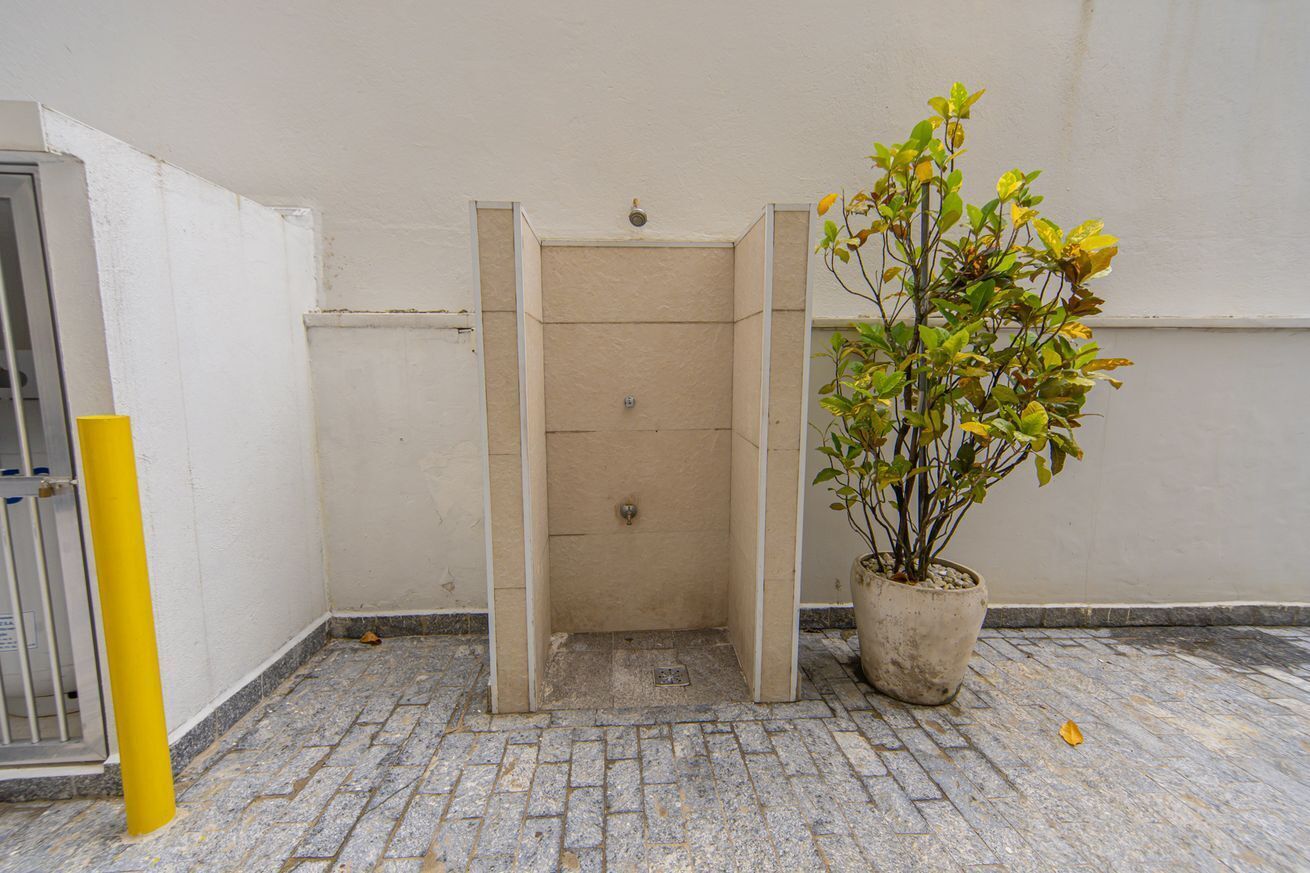 Un espacio pequeño y cerrado con una planta en maceta, un poste amarillo y un portón metálico.