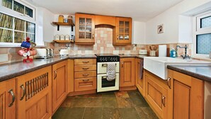 Una cocina con armarios de madera, una estufa y un ventanal.