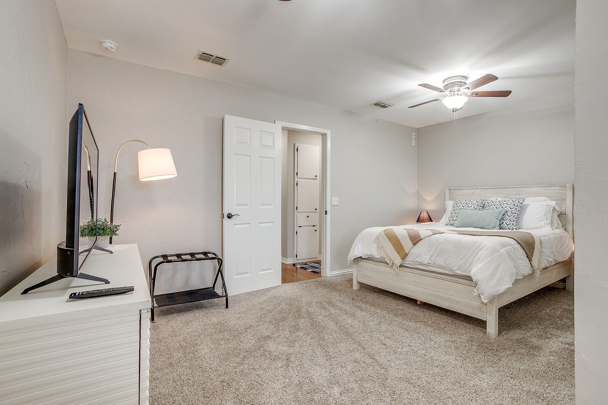 A bedroom with a bed, bedside lamp, ceiling fan, and a door leading to a closet.
