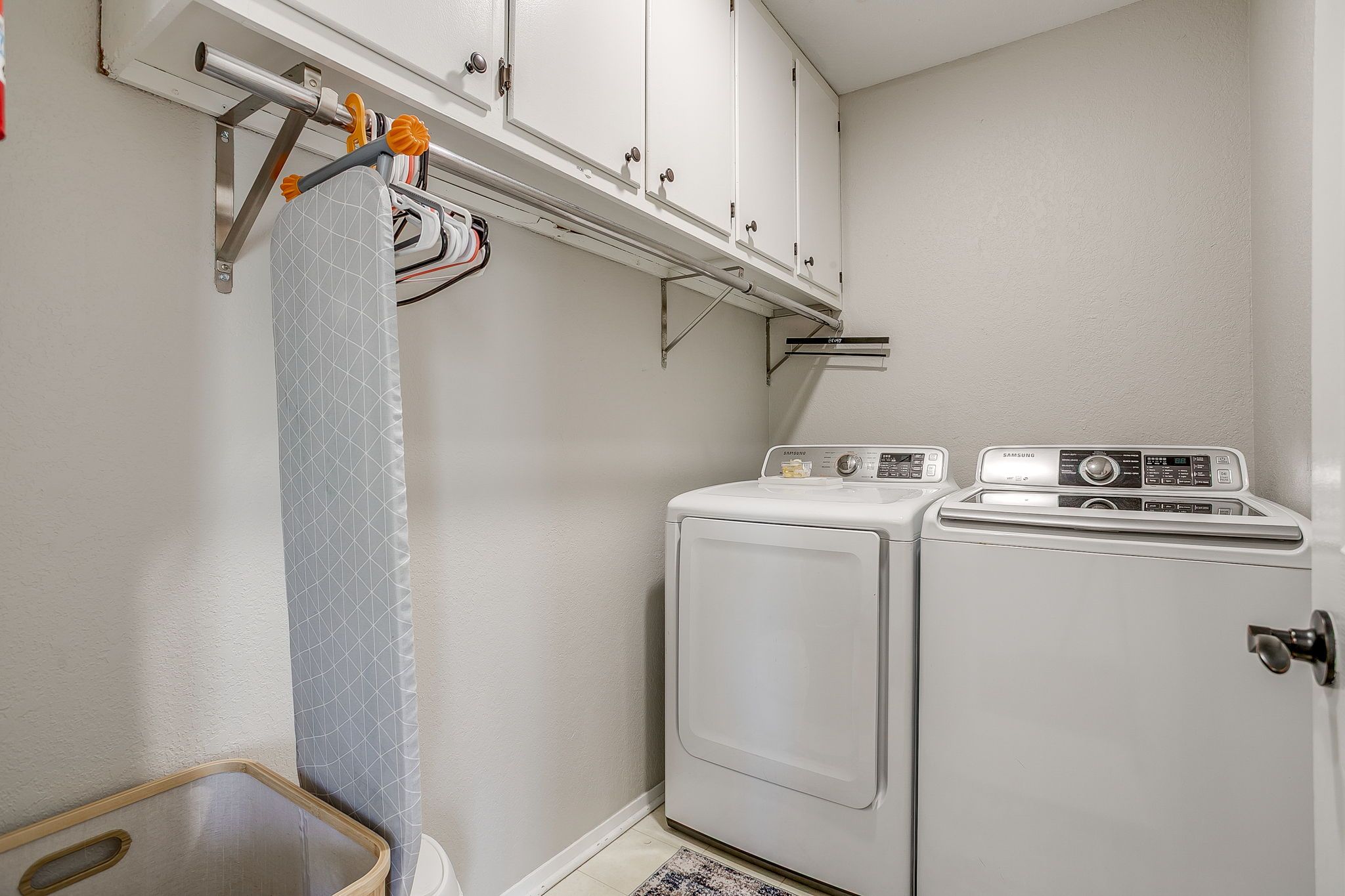 A laundry area with a washing machine and dryer, a drying rack, and a small wooden table.