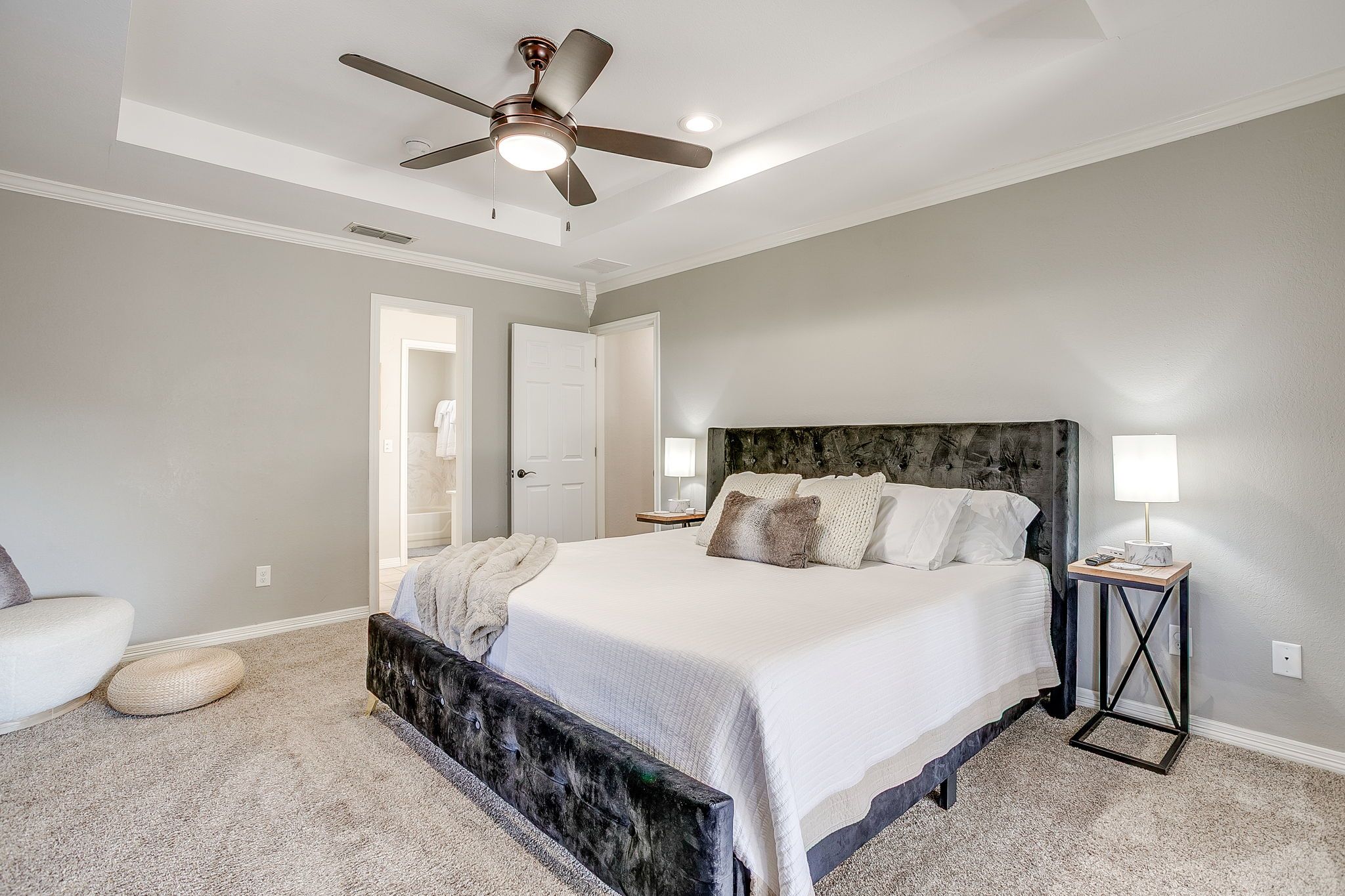 A bedroom with a bed, a ceiling fan, a nightstand, and a lamp.