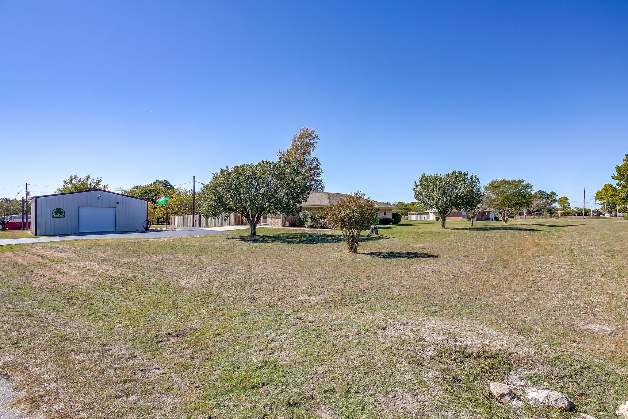 A grassy area with a building, trees, and a clear sky.