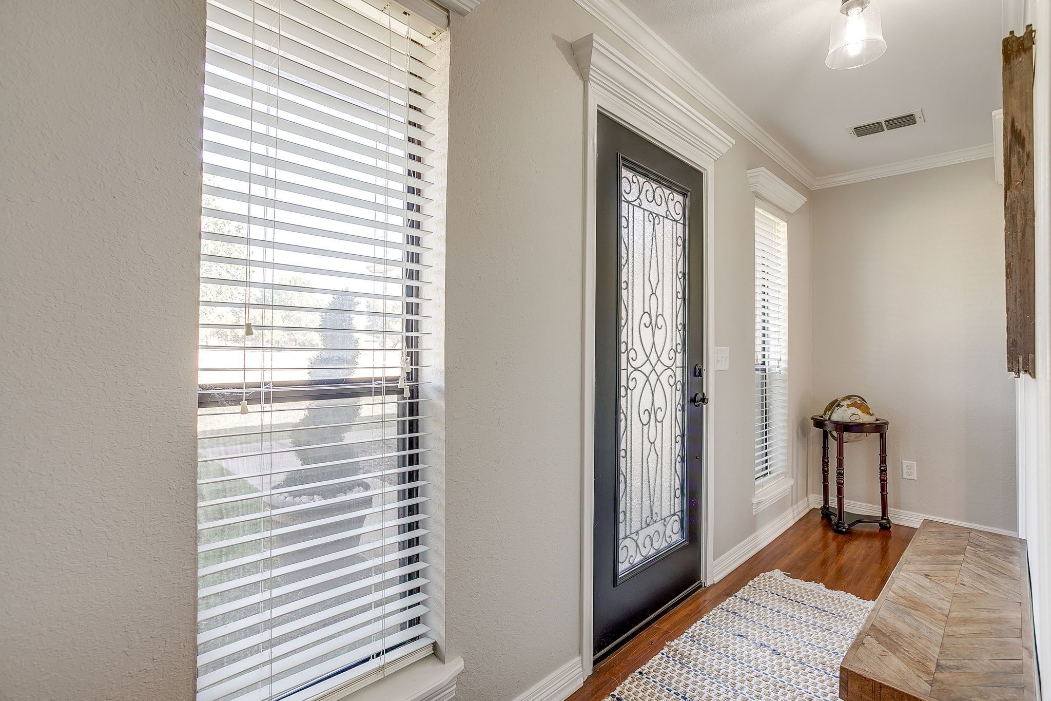 A hallway with a black door, white walls, and a wooden floor.