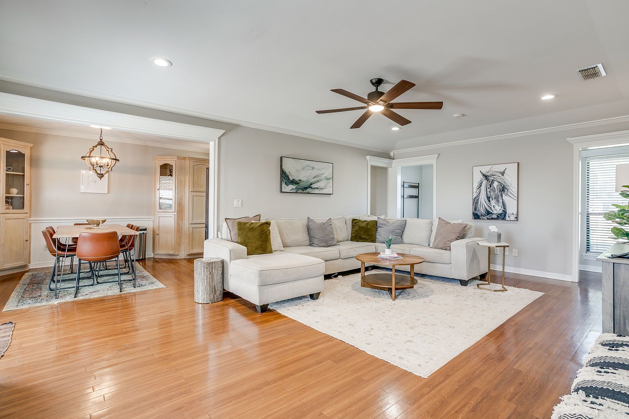A modern living room with a white sofa, a coffee table, and a dining area with a table and chairs.