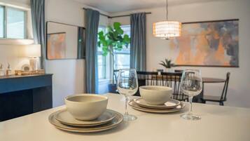 Une table à manger avec deux bols et deux verres à vin, une lampe et un tableau accroché au mur.
