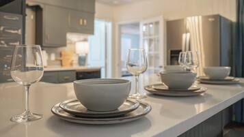 A modern kitchen with a white countertop, two bowls on plates, and two wine glasses.
