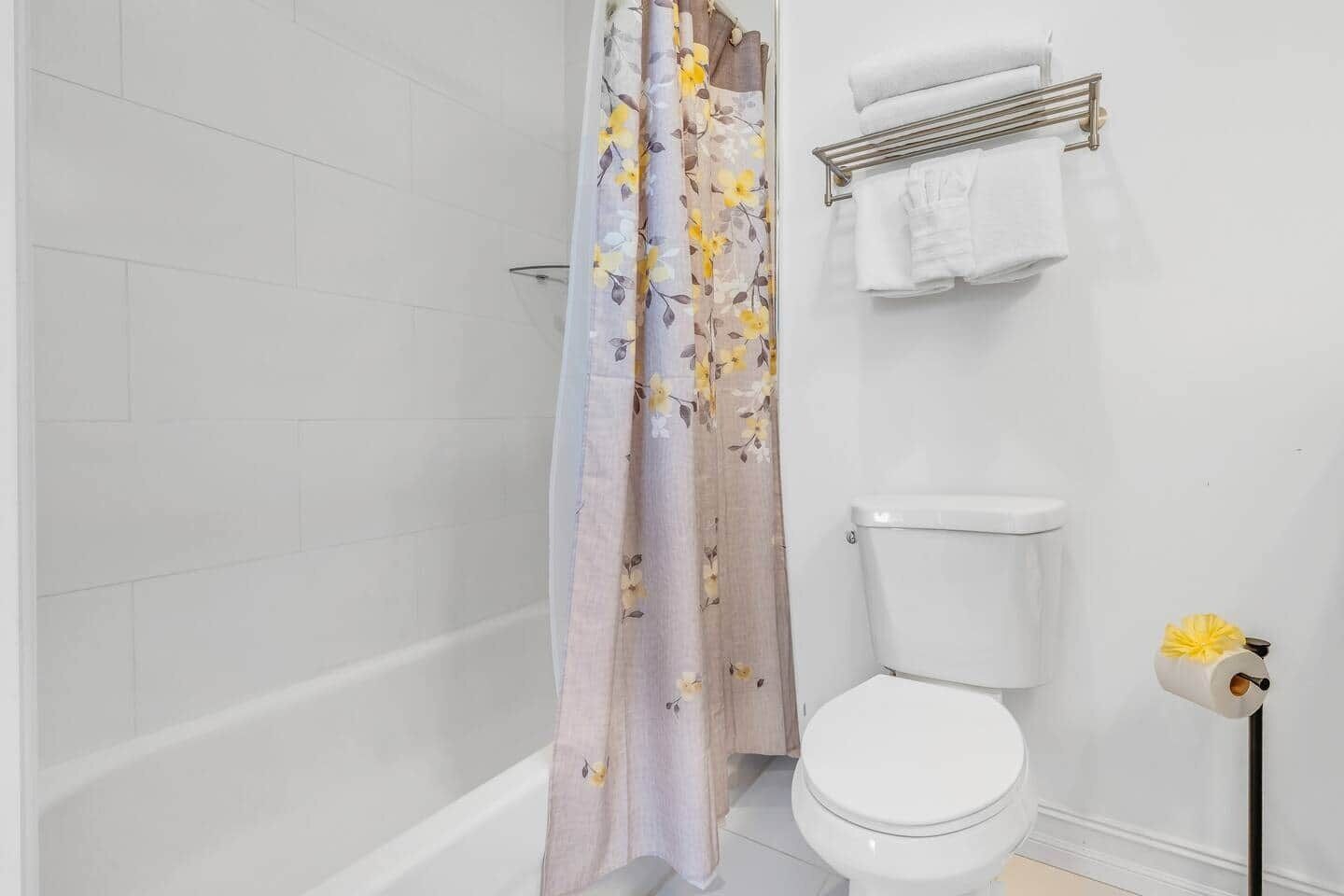 Une salle de bain avec un rideau de douche, des toilettes et un porte-serviettes.