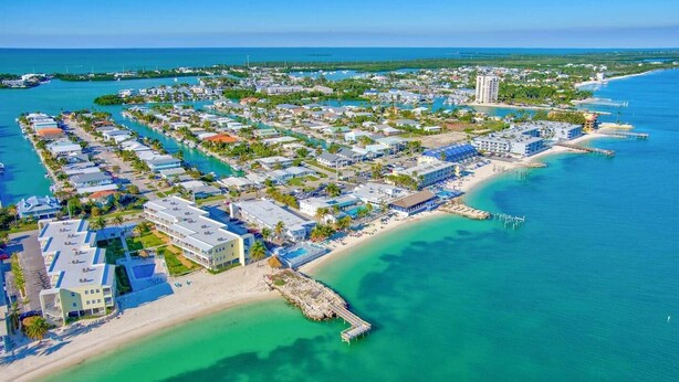 Eine Vogelperspektive eines Küstenresorts mit einer Marina, Strandimmobilien und einem Steg.