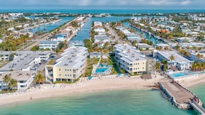 Ein Küstenresort mit mehreren Gebäuden, einem Strand und einem Yachthafen.