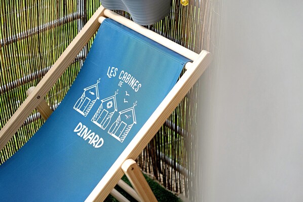 A blue lounge chair with a white text and house drawings, positioned against a bamboo fence.