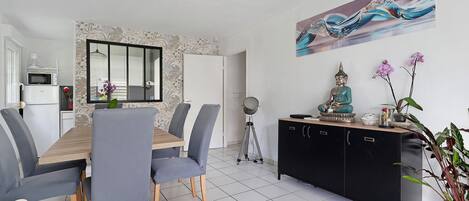 A dining area with a wooden table, grey chairs, a black cabinet, and a wall-mounted painting.