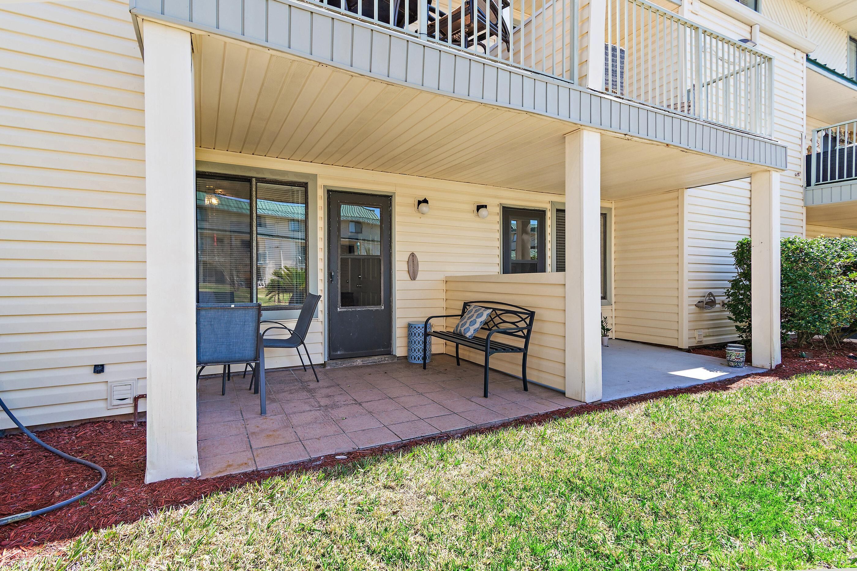 A covered patio with a bench, a door, and a window.
