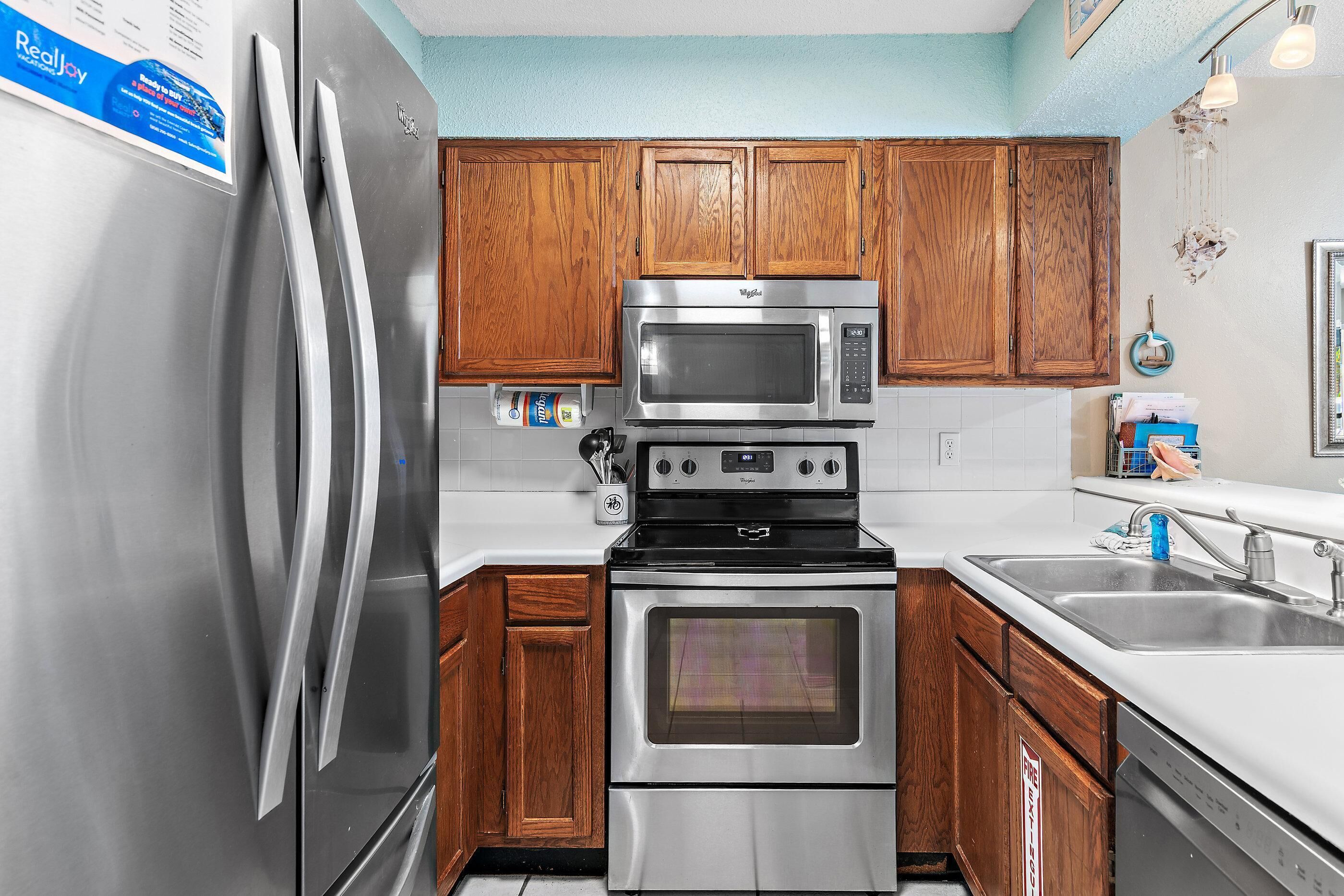 Una cocina con electrodomésticos de acero inoxidable, armarios de madera y encimera blanca.