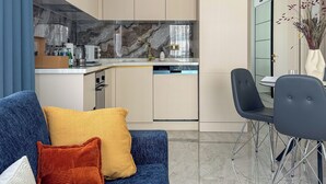 Een moderne keuken met een ingebouwde oven, magnetron en vaatwasser. Er is een eethoek met een tafel en stoelen.