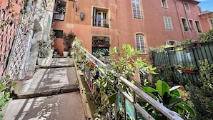 A multi-story building with balconies, a staircase, and potted plants. - Cocon du Senat 2 - Old Town (Niza)