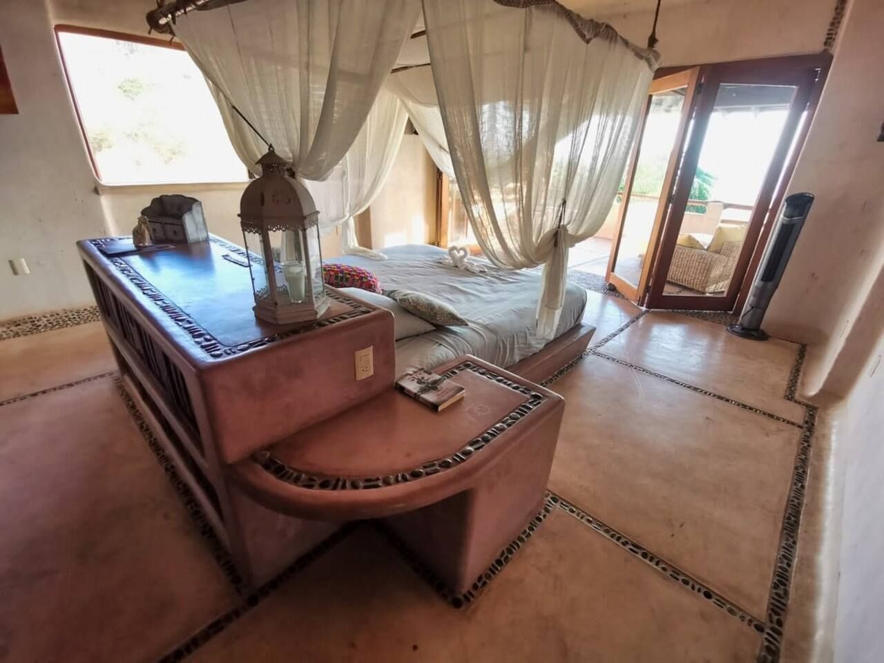 A bedroom with a bed, a nightstand, a lamp, and a window with curtains.