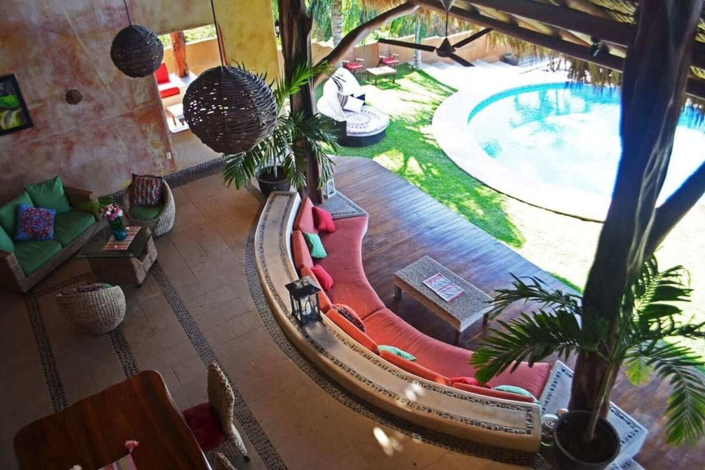 A poolside lounge with a curved seating area, a small table, and a hanging light fixture.