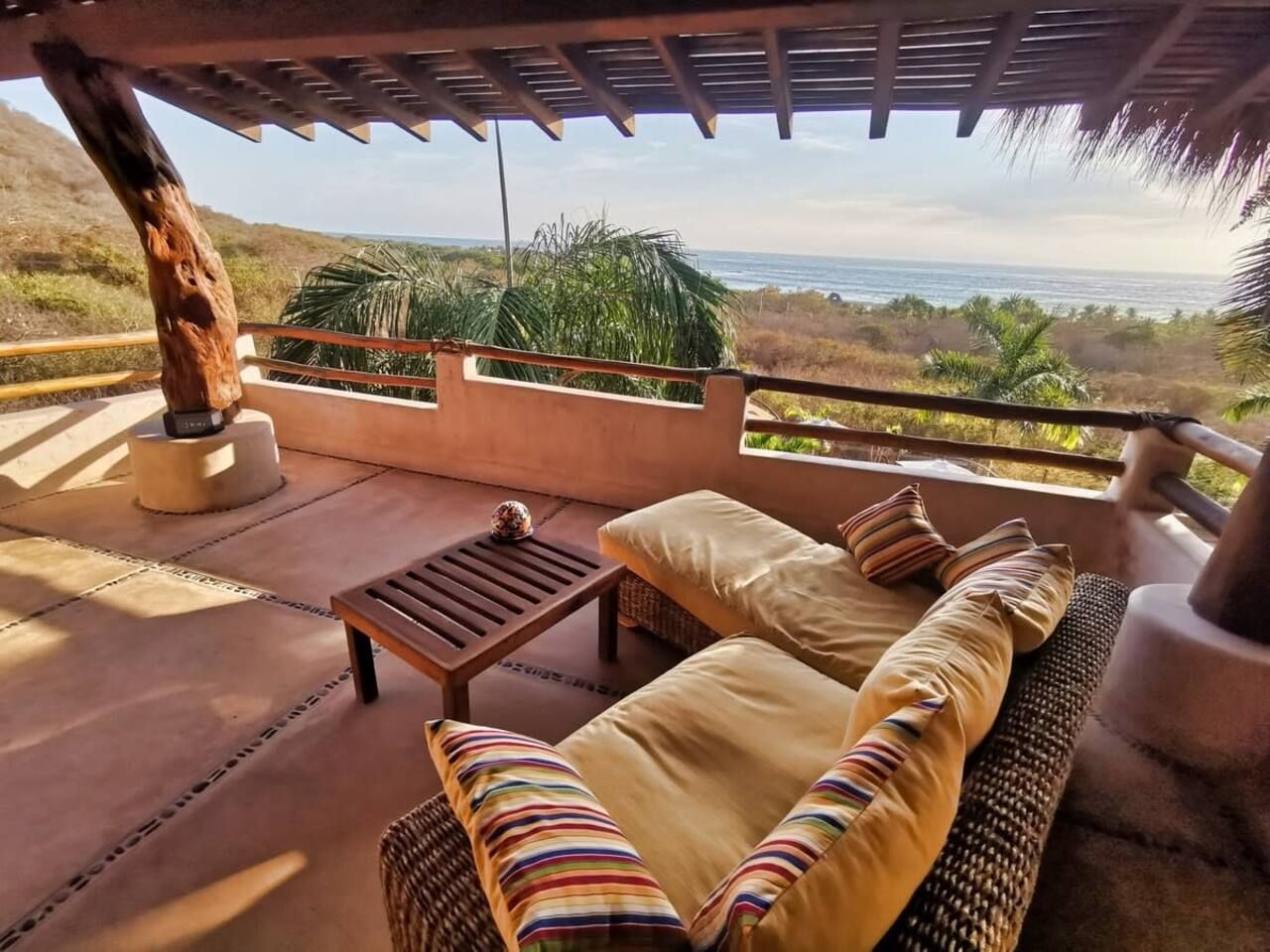 Un espace extérieur abrité, avec une table et des chaises, offrant une vue sur le paysage côtier.