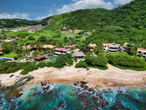 Ein Küstenresort mit Strandgrundstücken, einem Swimmingpool und üppiger Vegetation.