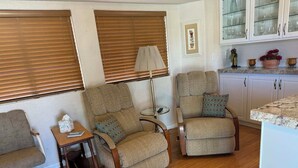 Un salon avec deux fauteuils, une petite table et une lampe.
