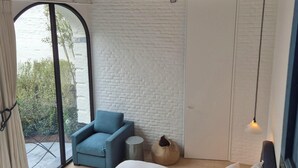A bedroom with a bed, a chair, a wardrobe, a round wicker basket, and a view through a large window. - Everelmus (Bruges)