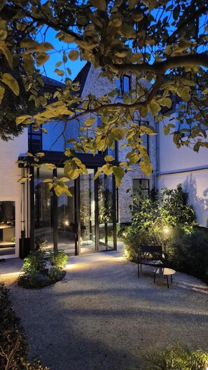 Un edificio moderno con entrada de vidrio, un patio de grava y una banca.