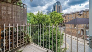 Een balkon met uitzicht op een stadstraat, een hoog gebouw en een bewolkte lucht.