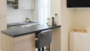 A modern kitchen with a central island, stainless steel appliances, and a flat-screen TV mounted on the wall. - Bright studio apartment on the outskirts of Paris (Clichy)