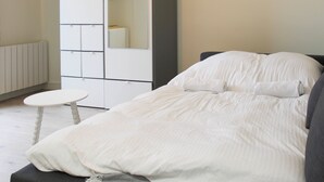 A bedroom with a bed, a small round table, and a wardrobe with a mirror. - Bright studio apartment on the outskirts of Paris (Clichy)