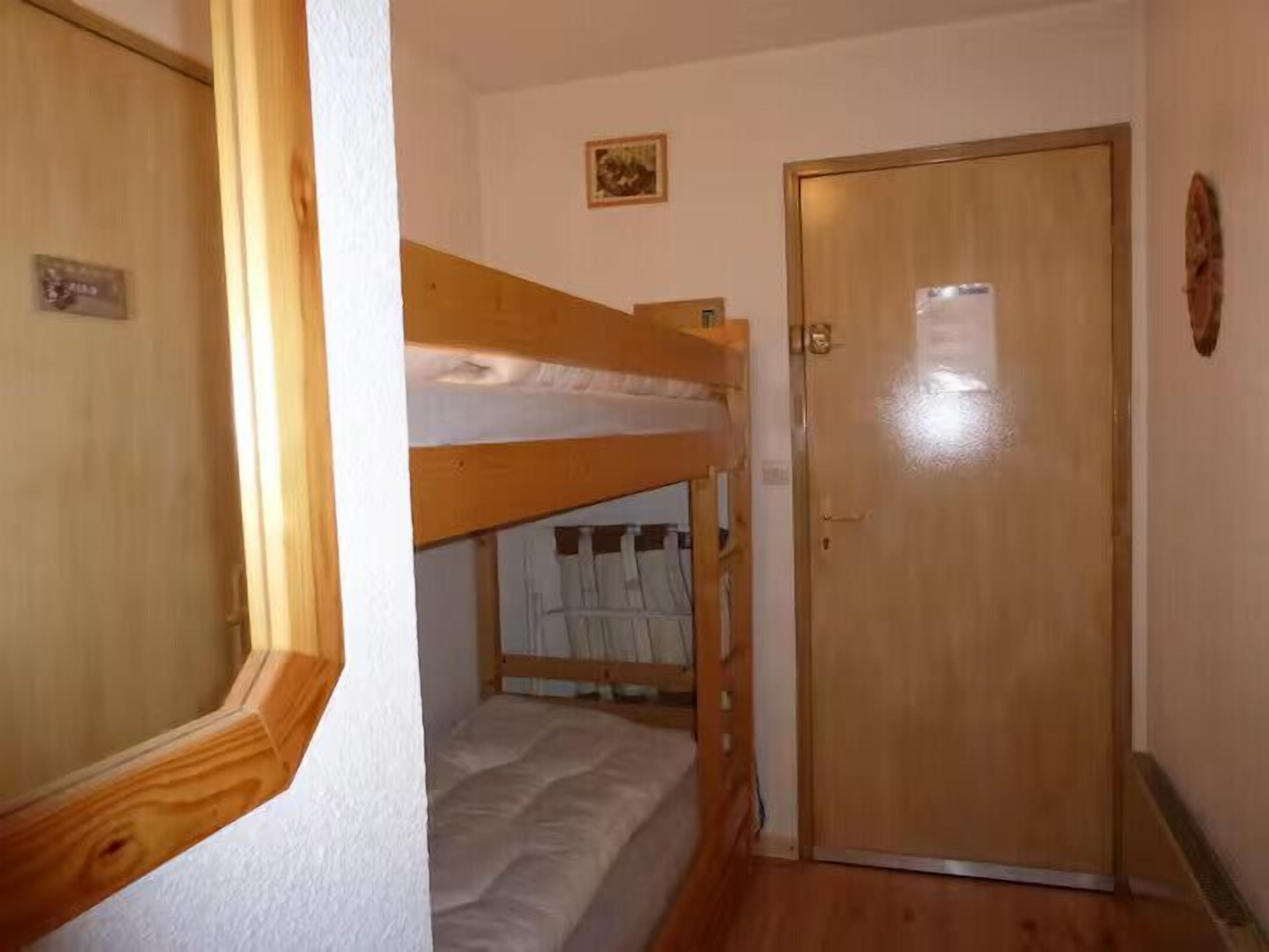 A room with a bunk bed, a wooden door, and a small picture on the wall.