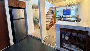 Une cuisine moderne dotée d’un réfrigérateur encastré, d’un escalier en bois et d’un coin repas avec une table ronde.