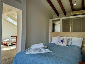 A hotel room with a bed, a nightstand, a window with shutters, and a view of another room. - Loft con Jacuzzi Privado (Ixtapa)