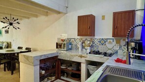 Une cuisine compacte équipée d’une cuisinière intégrée, d’un évier et d’un coin repas avec une table et des chaises.