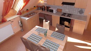 Una cucina compatta con lavello, fornelli, microonde e pensili.