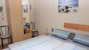 Una camera da letto con un letto, un comodino, una scrivania, una sedia, un armadio e uno specchio.