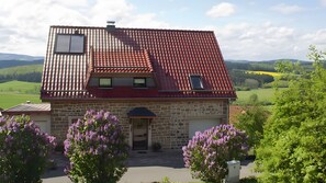 Ein zweistöckiges Haus mit rotem Ziegeldach, Steinmauern und einem Hauseingang.