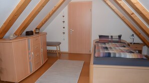 Une chambre avec un plafond de style industriel, un lit, un bureau et une armoire.