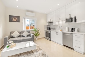 A modern kitchen with white cabinets, a built-in oven, and a microwave.