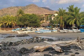 A beach with boats, palm trees, and a mountain in the background. - Luxury Sofia 6 in luxury condo (La Majahua)