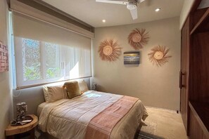 A bedroom with a bed, a window, a ceiling fan, and wall decor.