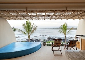 A covered outdoor seating area with a pool, two wooden chairs, and a grill.
