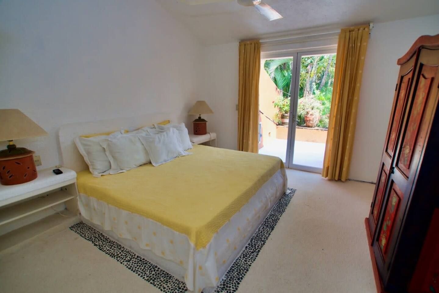 A bedroom with a bed, a nightstand, a lamp, a wardrobe, and a sliding glass door leading to a balcony.