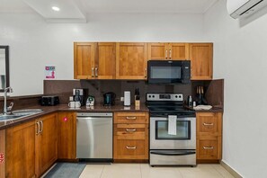 A kitchen with wooden cabinets, a microwave, a dishwasher, and an oven. - 2BR Condo w/ Pool & Balcony, 1 Min to Eagle Beach (Noord)