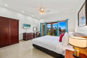 Une chambre d’hôtel équipée d’un lit, d’un bureau, d’une chaise, d’un ventilateur de plafond et offrant une vue sur l’extérieur.